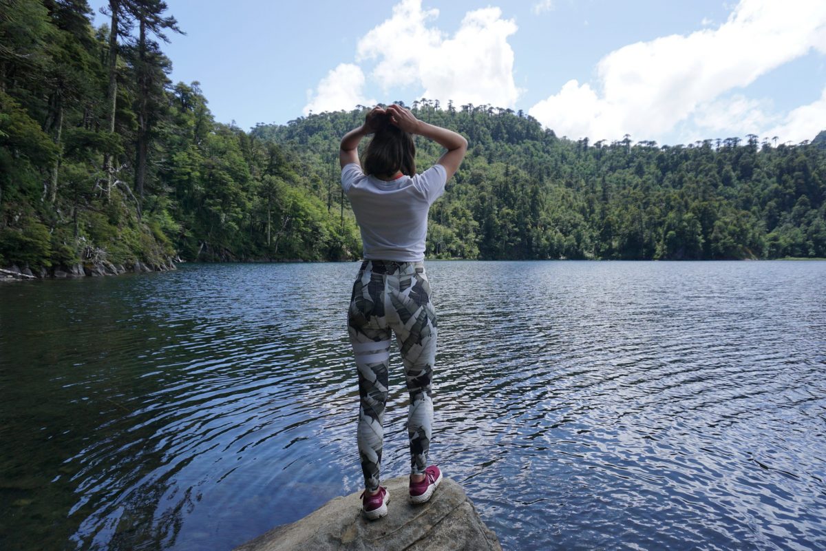 Vrouw staand op een rots bij een meer met een sportlegging met print aan