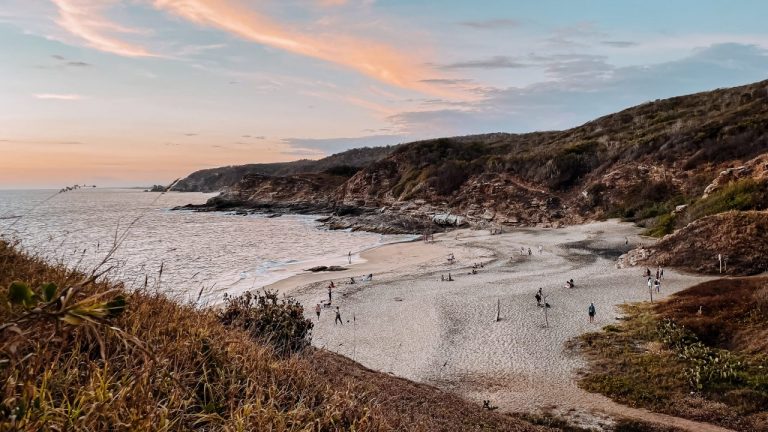Strand in Mexico gelegen in een baai omringt door heuvels tijdens zonsondergang