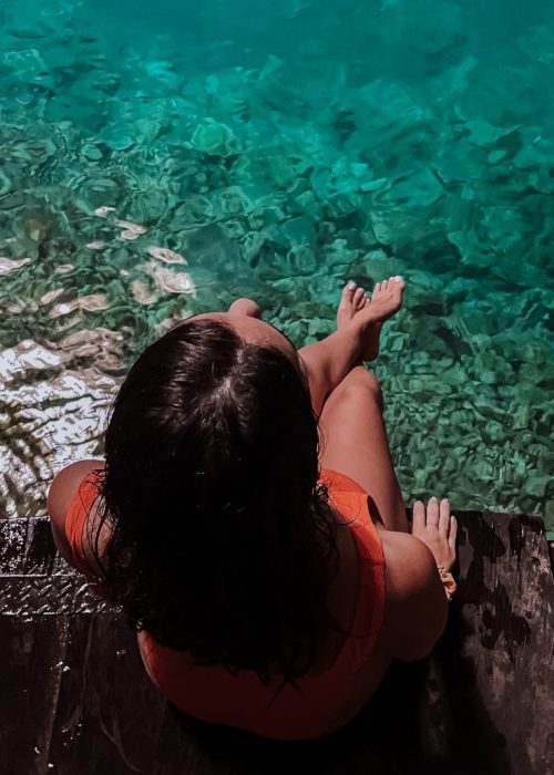 Bovenaanzicht van een vrouw die op de rand van een houten platform zit in Cenote Xux'Ha in Yucatan Mexico