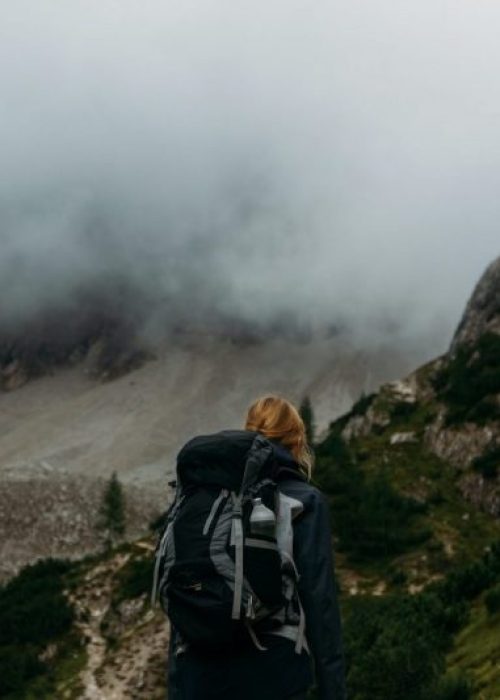 Vrouw met een backpack op haar rug die door de bergen wandelt